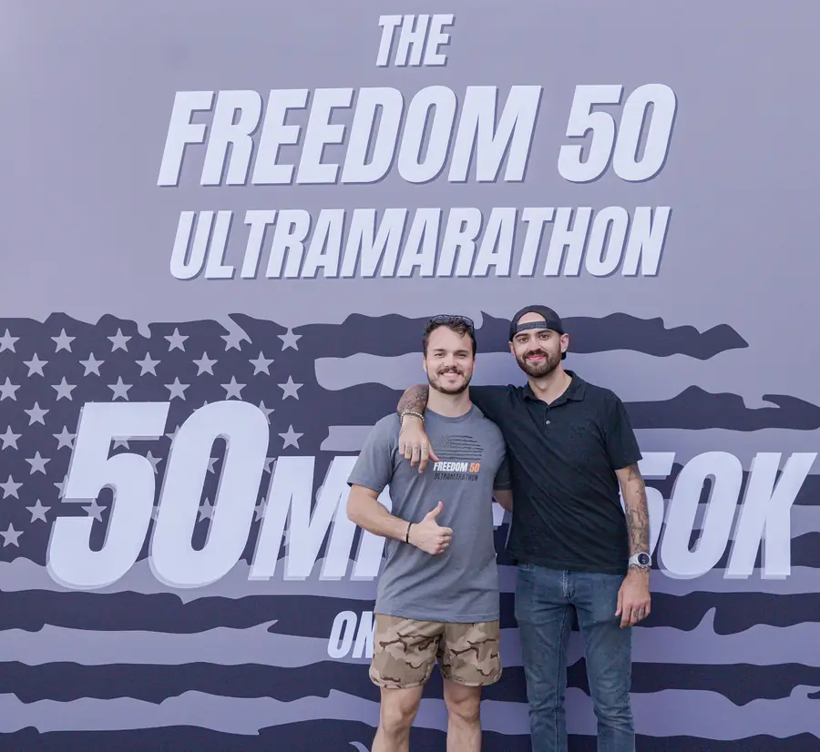 Two men in front of the Freedom 50 Ultramarathon 50 mile and 50K backdrop