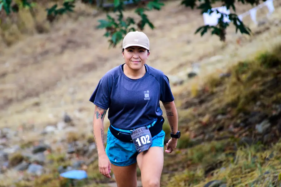 Smiling trail runner climbing a rocky hillside during an ultramarathon