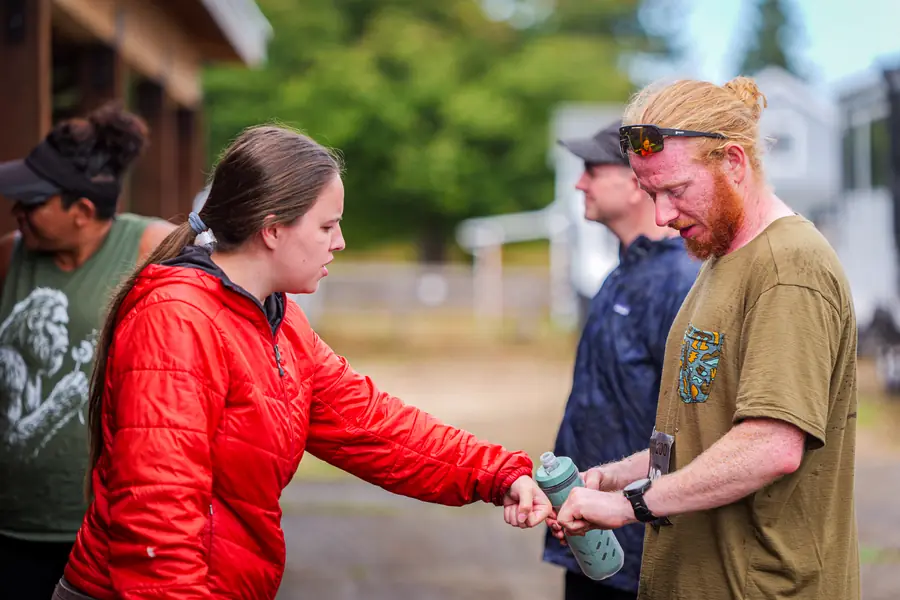 Crew member helping an ultramarathon runner with his bottle at an aid station